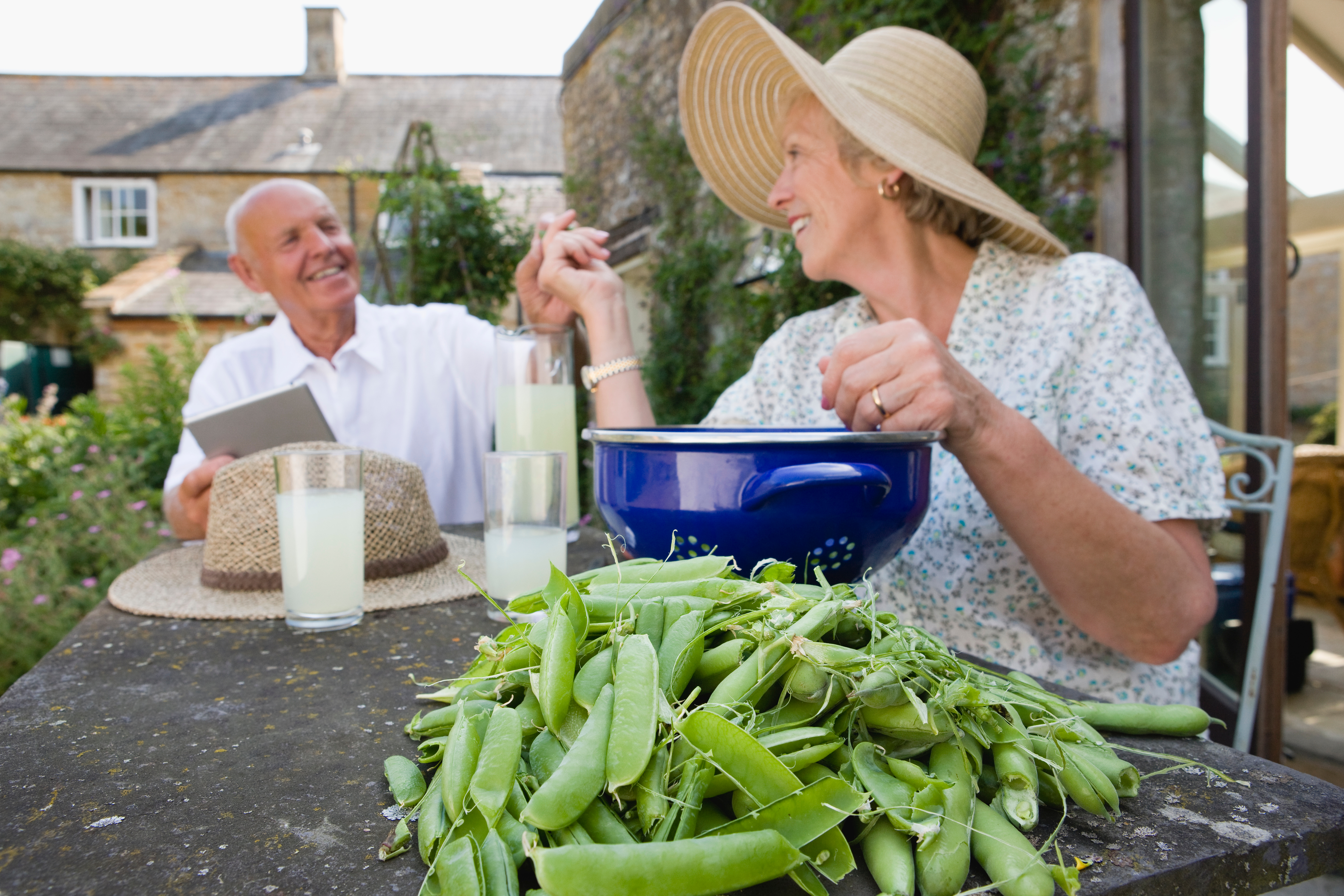 Smiling senior couple enjoying peas and lemonade outdoors