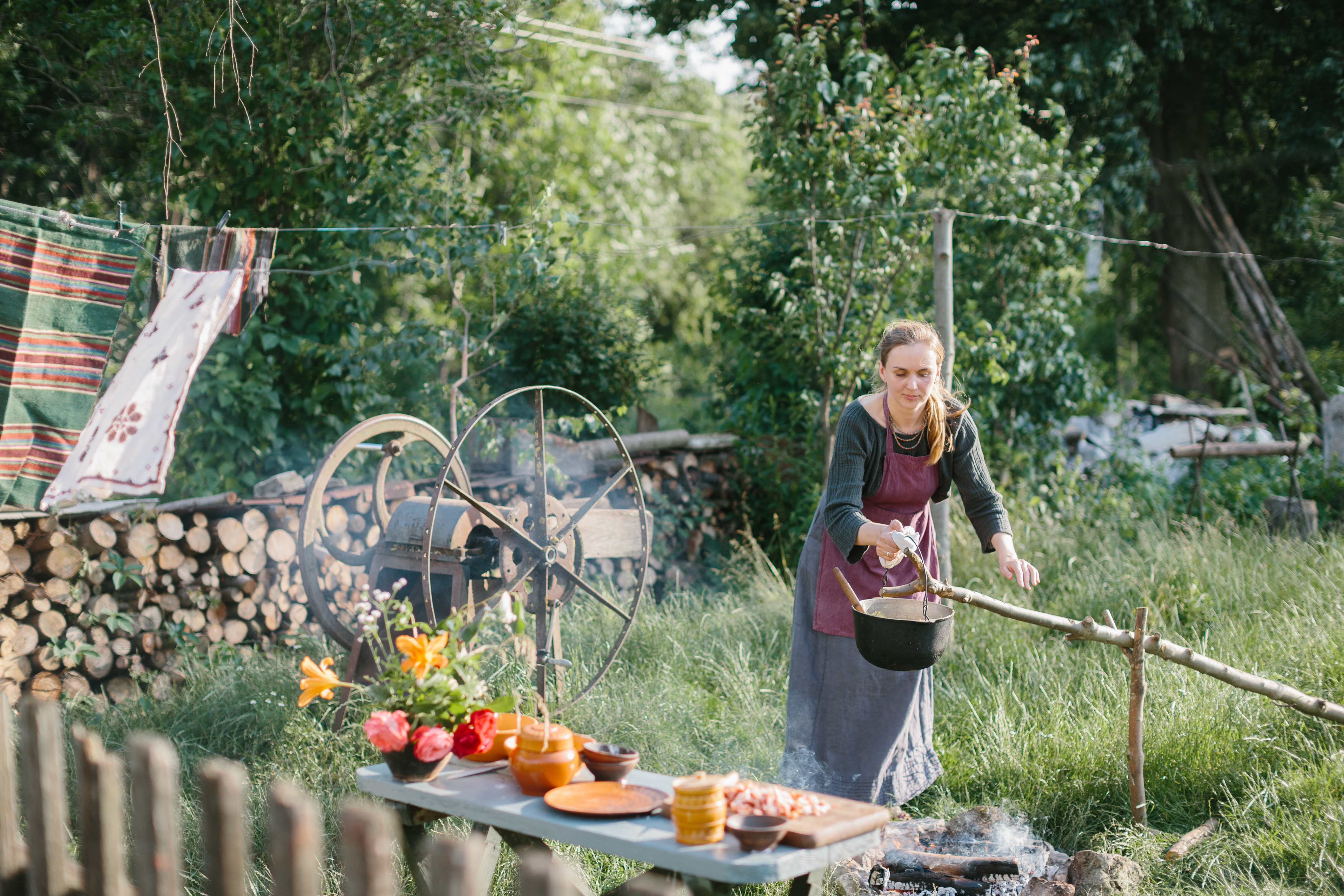 Woman cooking outdoors in a rustic garden using an open fire